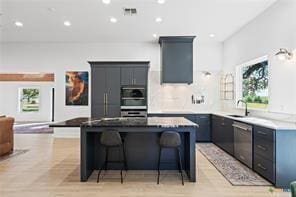 kitchen with a kitchen island, double oven, dishwasher, sink, and a breakfast bar area