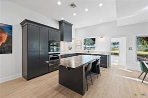 kitchen with stainless steel oven, a breakfast bar, a kitchen island, and light hardwood / wood-style flooring