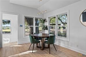 dining area featuring hardwood / wood-style flooring, vaulted ceiling, and track lighting