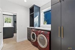 clothes washing area featuring washer and dryer and light hardwood / wood-style flooring