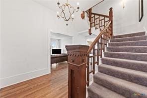 stairway with wood-type flooring and a chandelier