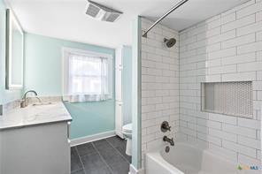 full bathroom with tiled shower / bath, vanity, and toilet