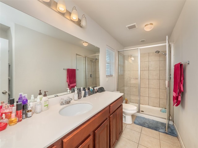 bathroom featuring tile patterned flooring, vanity, a shower with shower door, and toilet