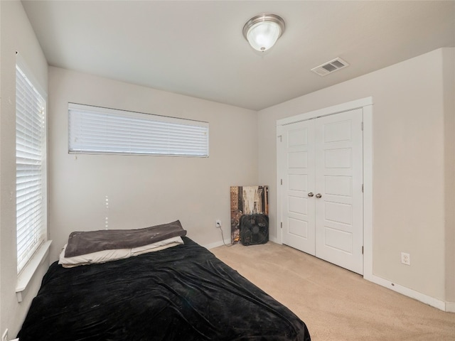 bedroom with light carpet and a closet