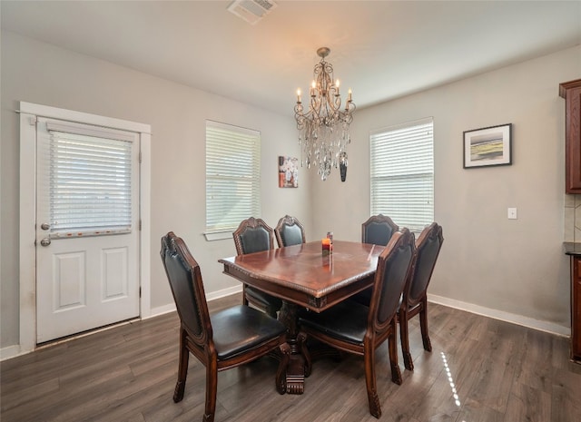 dining space with dark wood-type flooring, a healthy amount of sunlight, and an inviting chandelier