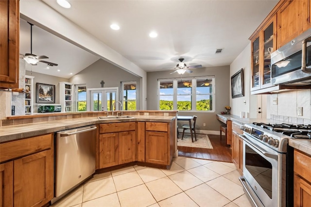 kitchen featuring light tile patterned flooring, sink, vaulted ceiling, stainless steel appliances, and decorative backsplash