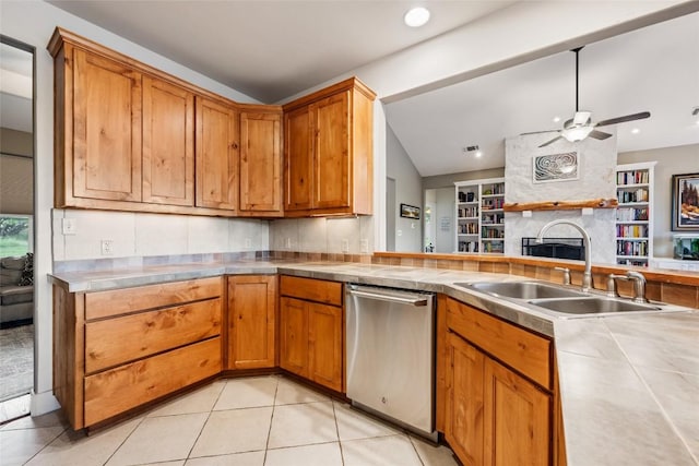 kitchen with light tile patterned flooring, a fireplace, dishwasher, lofted ceiling, and sink