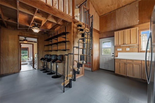 interior space with black fridge, a healthy amount of sunlight, and wood walls