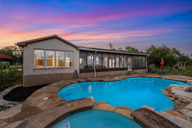 pool at dusk with a sunroom