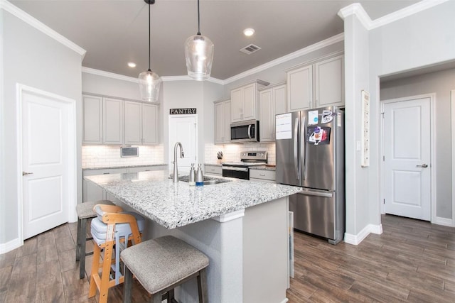 kitchen with light stone counters, sink, a center island with sink, and appliances with stainless steel finishes