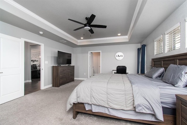 carpeted bedroom with a tray ceiling, ornamental molding, and ceiling fan