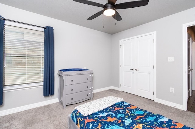 bedroom featuring ceiling fan, carpet flooring, a closet, and a textured ceiling