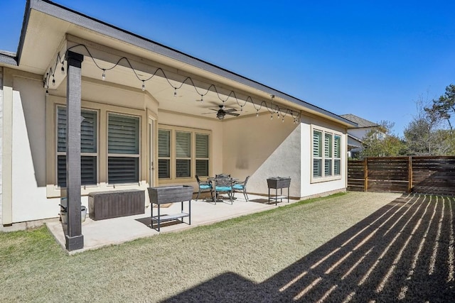 rear view of house featuring ceiling fan, a patio area, and a lawn