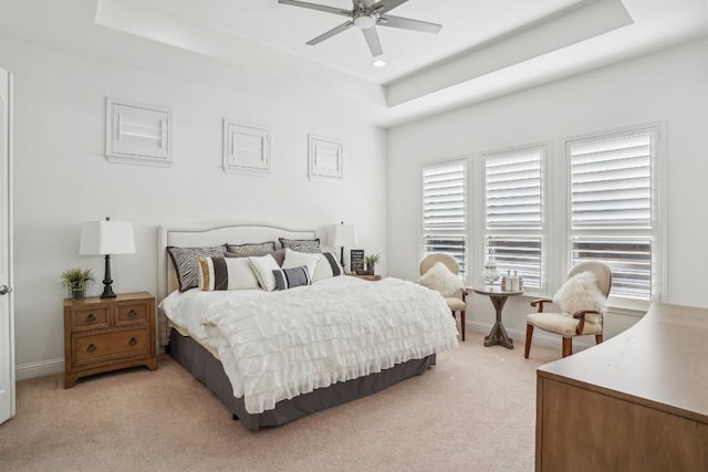 carpeted bedroom featuring a tray ceiling and ceiling fan