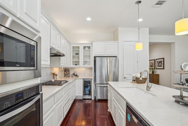 kitchen featuring wine cooler, sink, white cabinetry, decorative light fixtures, and appliances with stainless steel finishes