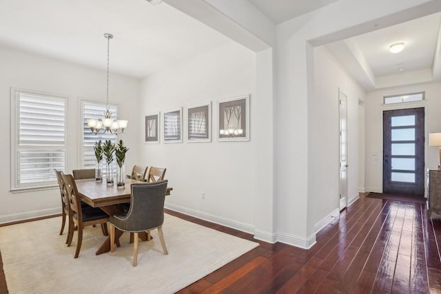 dining room with dark hardwood / wood-style floors and an inviting chandelier