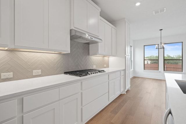 1243 Robin Trl, Round Rock, TX 78681 - kitchen featuring ventilation hood, light countertops, white cabinets, decorative backsplash, and light wood-type flooring