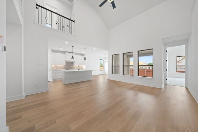 1243 Robin Trl, Round Rock, TX 78681 - unfurnished living room with ceiling fan, light wood finished floors, high vaulted ceiling, baseboards, and a sink