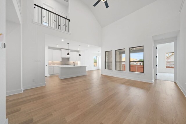1243 Robin Trl, Round Rock, TX 78681 - unfurnished living room featuring a ceiling fan, light wood-type flooring, and high vaulted ceiling
