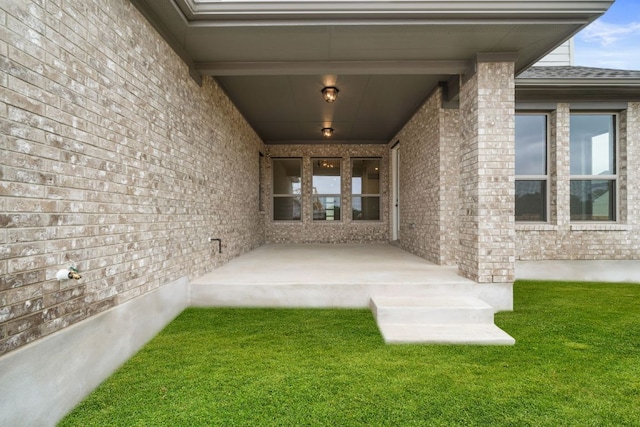 1243 Robin Trl, Round Rock, TX 78681 - view of exterior entry featuring brick siding, a lawn, and roof with shingles