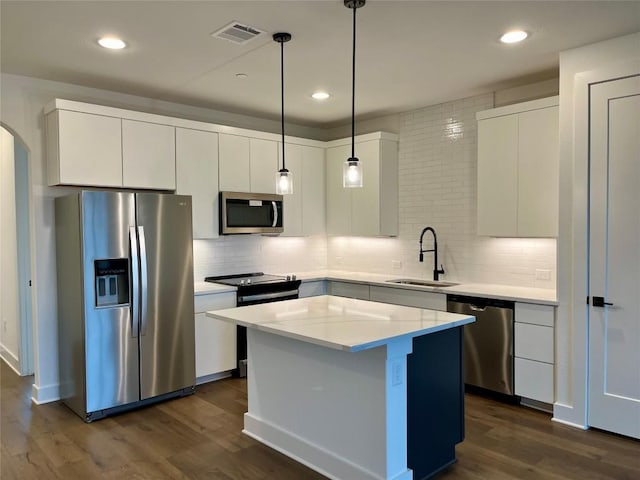 kitchen with stainless steel appliances, white cabinetry, hanging light fixtures, and sink