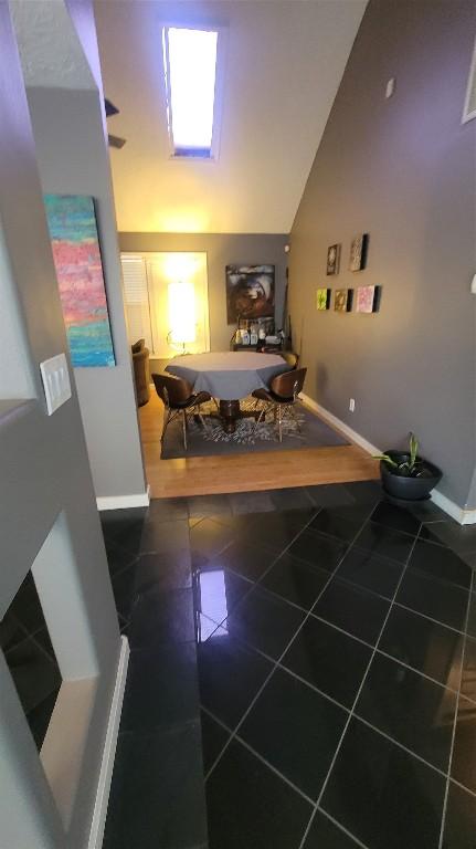 hallway featuring tile patterned flooring and vaulted ceiling