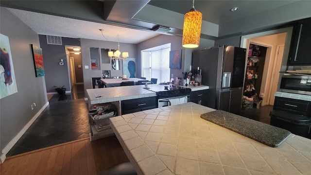 12410 Twin Creek Rd, Manchaca, TX 78652 - kitchen with stainless steel refrigerator with ice dispenser, tile countertops, black range with electric cooktop, visible vents, and a notable chandelier
