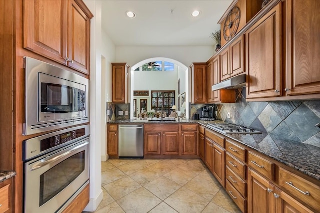 kitchen featuring tasteful backsplash, sink, stainless steel appliances, and dark stone counters