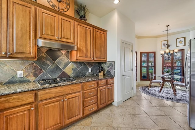 kitchen featuring an inviting chandelier, tasteful backsplash, decorative light fixtures, dark stone countertops, and stainless steel appliances