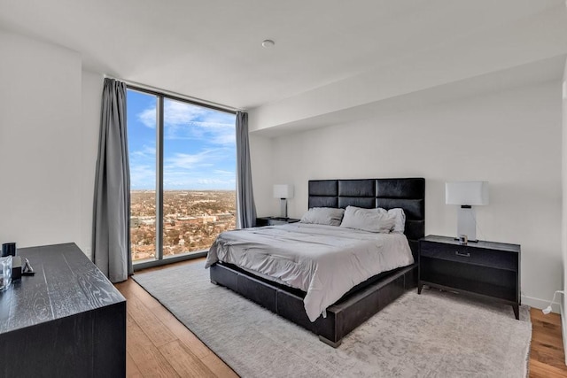 bedroom featuring floor to ceiling windows and light hardwood / wood-style floors