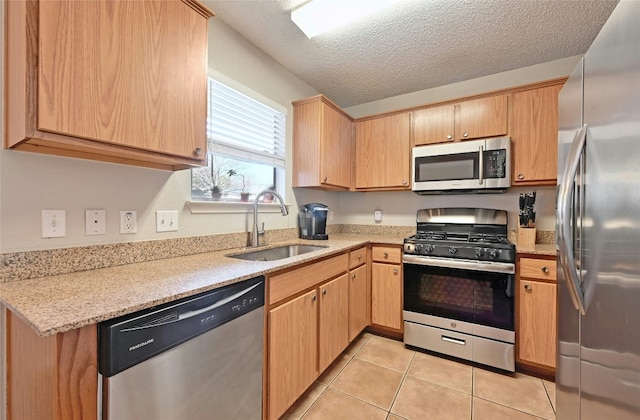 kitchen with sink, light tile patterned floors, light stone counters, stainless steel appliances, and a textured ceiling