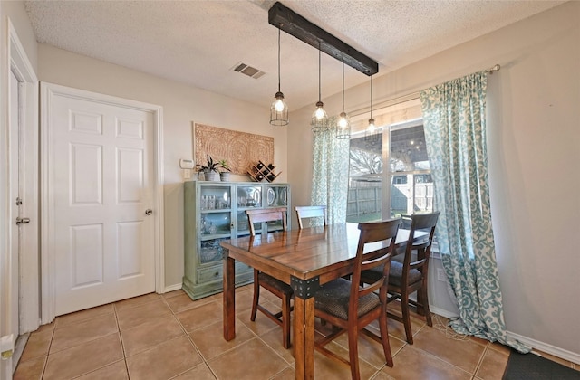 tiled dining area featuring beamed ceiling and a textured ceiling