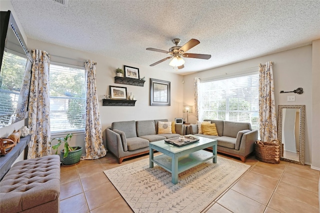 tiled living room with ceiling fan, plenty of natural light, and a textured ceiling