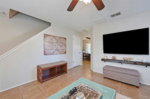 tiled living room with ceiling fan and a textured ceiling