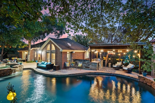 pool at dusk with an in ground hot tub, an outdoor hangout area, an outdoor bar, and a patio area