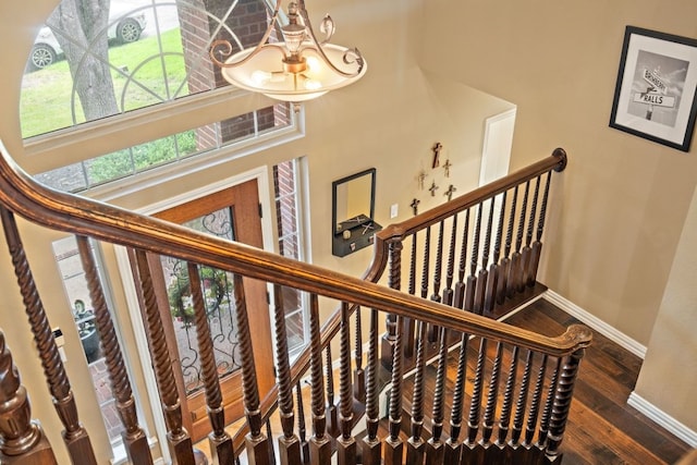 stairway with a notable chandelier, hardwood / wood-style flooring, and a high ceiling