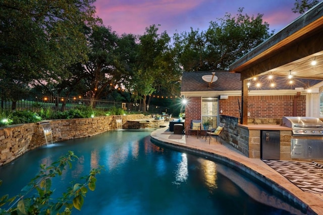 pool at dusk featuring pool water feature, area for grilling, and a patio area