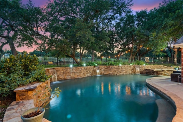 pool at dusk with pool water feature and a patio area