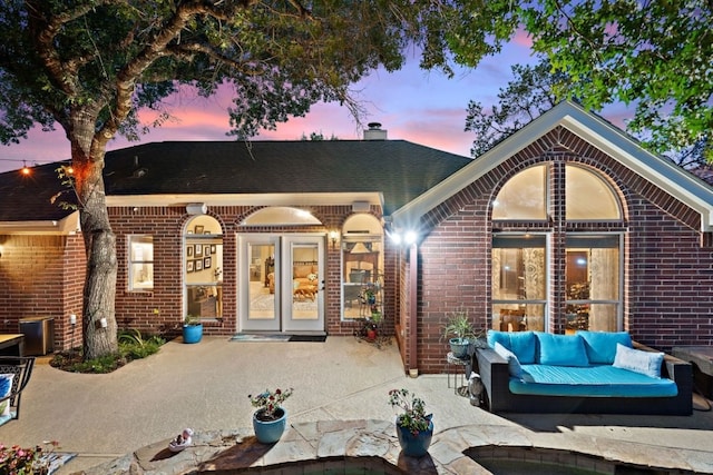 104 Fenway Ct, Lakeway, TX 78734 - back of property at dusk featuring brick siding, outdoor lounge area, a patio area, and a chimney