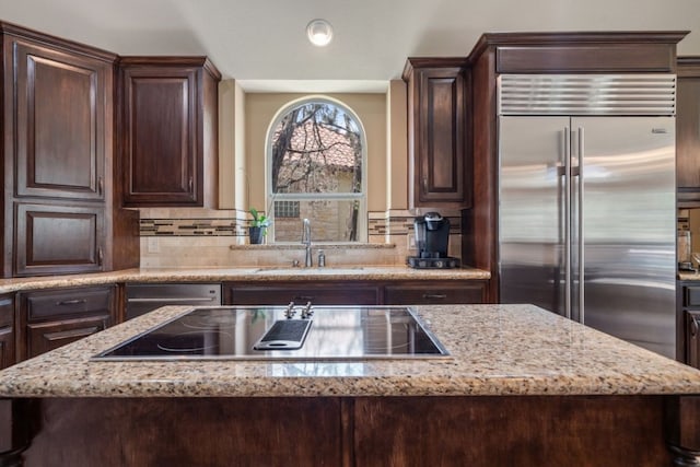 104 Fenway Ct, Lakeway, TX 78734 - kitchen with built in fridge, stovetop with downdraft, dark brown cabinetry, and light stone countertops