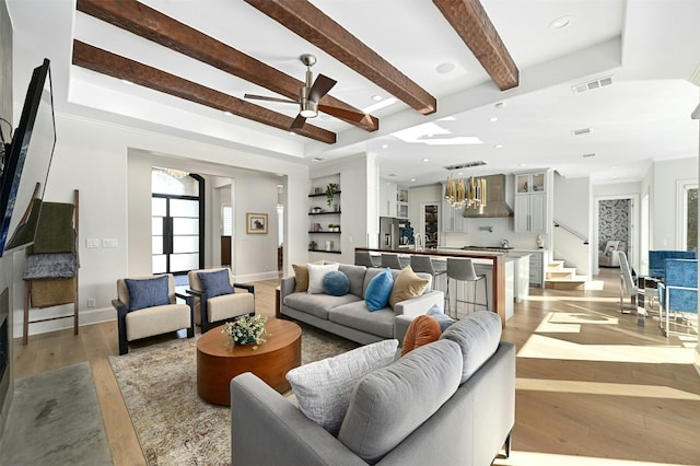 living room with ceiling fan, beam ceiling, and light hardwood / wood-style flooring