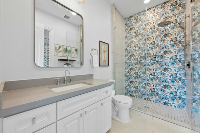 bathroom with tiled shower, vanity, toilet, and tile patterned flooring