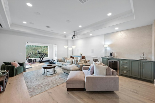 living room with beverage cooler, a tray ceiling, and wet bar