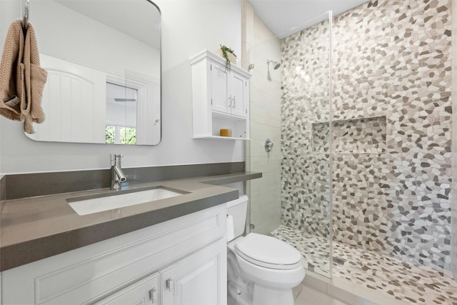 bathroom featuring vanity, a shower with door, and toilet