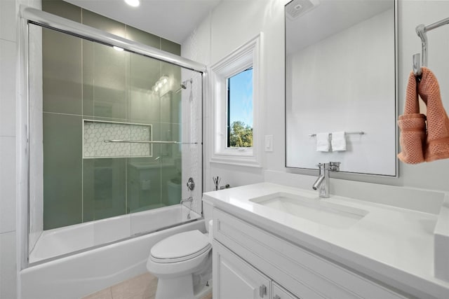 full bathroom with bath / shower combo with glass door, vanity, tile patterned floors, and toilet