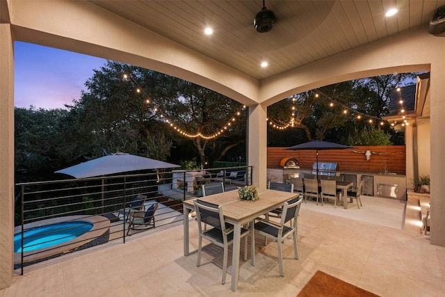 patio terrace at dusk with area for grilling and a hot tub