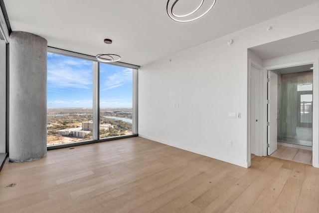 empty room with floor to ceiling windows and light wood-type flooring