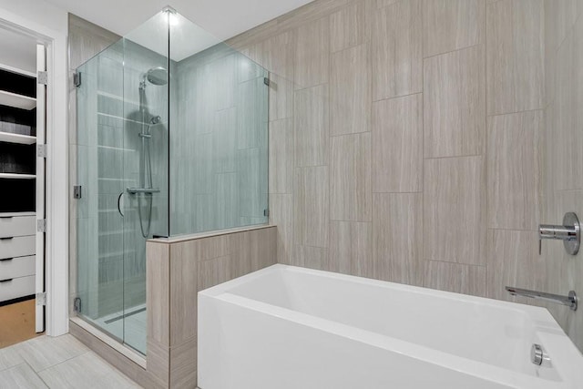 bathroom with tile walls and independent shower and bath