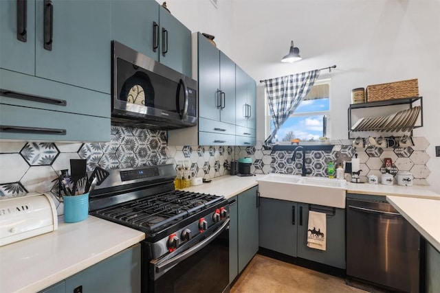 kitchen featuring stainless steel appliances, sink, blue cabinetry, and decorative backsplash