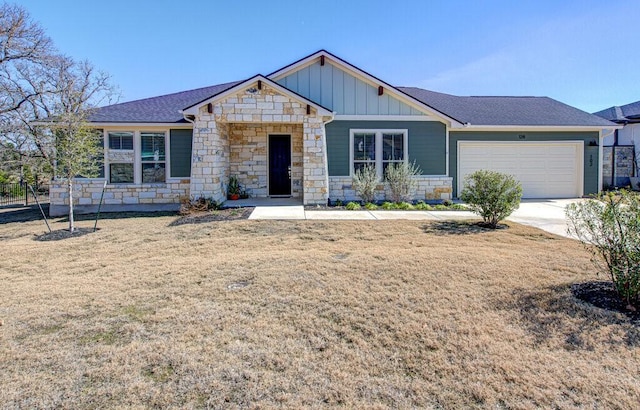 view of front of home with an attached garage, board and batten siding, stone siding, driveway, and a front lawn